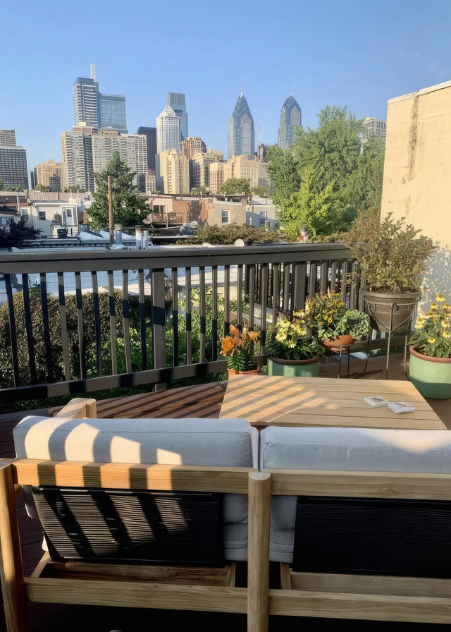 Customer photo - Neighbor teak chair with white cushion on a rooftop deck with potted flowers and Philadelphia city skyline in the background